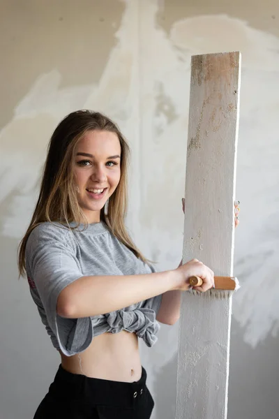 Neşeli kız genç tasarımcı tahtaya koruyucu bir boya koyar. — Stok fotoğraf