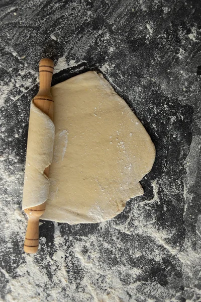 Recept på deg till bröd. Rullande stift på bordet rullar kakan, rå deg och mjöl på bordet — Stockfoto
