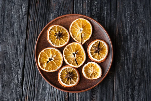 Круглые ломтики сушеного апельсина в тарелке на фоне дерева — стоковое фото