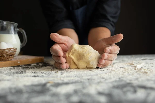 Ingredienserna till pizza är på bordet, kockens manliga händer knåda degen. — Stockfoto
