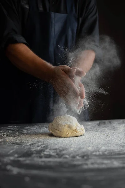 Chef in the kitchen, male hands knead the dough, clap hands, a cloud of flour — Stock Photo, Image