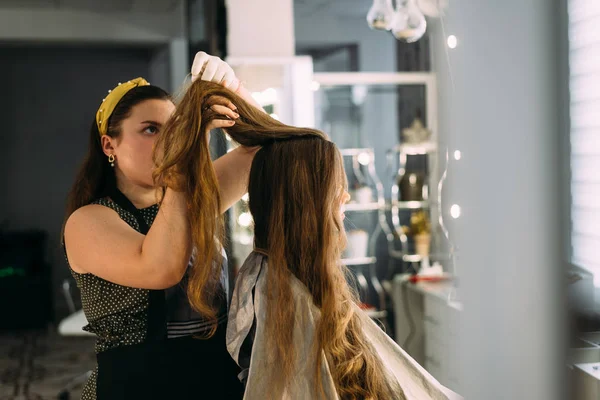 beautiful girl with very long hair, girl hairdresser doing hair styling.