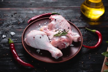 Siyah arka planda çiğ tavuk bacağı ve acı kırmızı biber.,