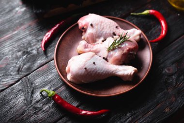 Üç çiğ tavuk bacağı tabakta, acı biber ve baharatlar mutfakta..