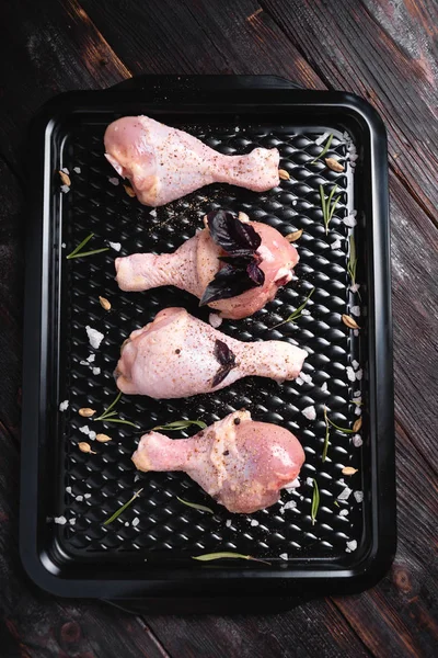 Siyah bir arka plan üzerinde tavuk bacakları. Tabakta taze çiğ tavuk bacağı aranjmanı. Üstte görüntü.