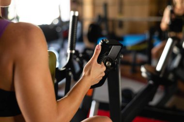 Spor salonundaki simülatörün metal saplarını tutan güçlü sporcu kadınların elleri.
