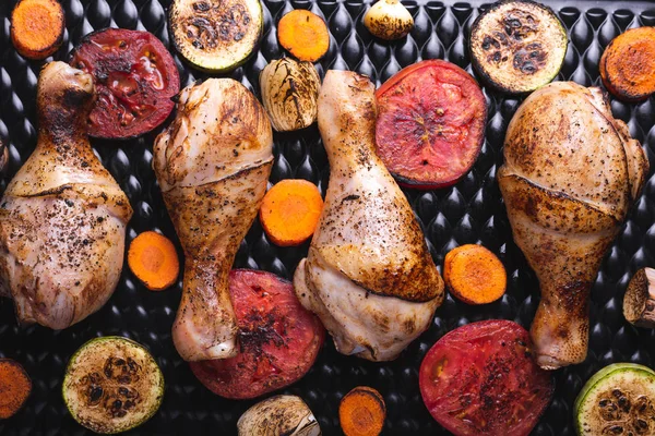 Lahodné jídlo na stole, grilované kuřecí stehýnka, voňavá krusta, uzená zelenina — Stock fotografie