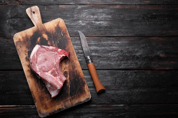 Raw pork meat, a fresh piece lies on a cutting board, a kitchen table made of wood. — Stockfoto