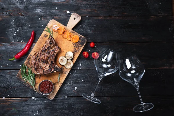 Zaftos grillezett sertéshús egy üveg borral és poharakkal egy öreg fán — Stock Fotó