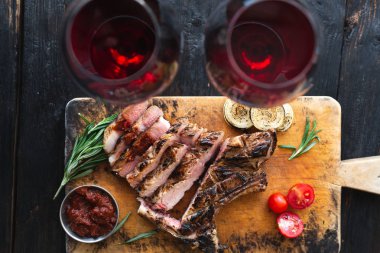 Kesme tahtasında iyi pişmiş biftek, lezzetli aromalı et dilimleri, iki kişilik akşam yemeği..