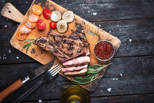 Grilled striploin sliced steak on cutting board over stone table.
