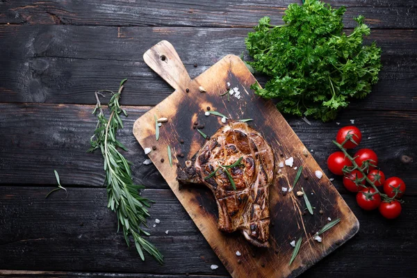 A whole piece of meat on a cutting board, juicy and aromatic steak, grilled, vegetables on the table. — Stockfoto