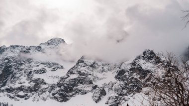 Alplerde tatiller, kayalık dağların karlı zirveleri, dağların üzerindeki bulutlar.,