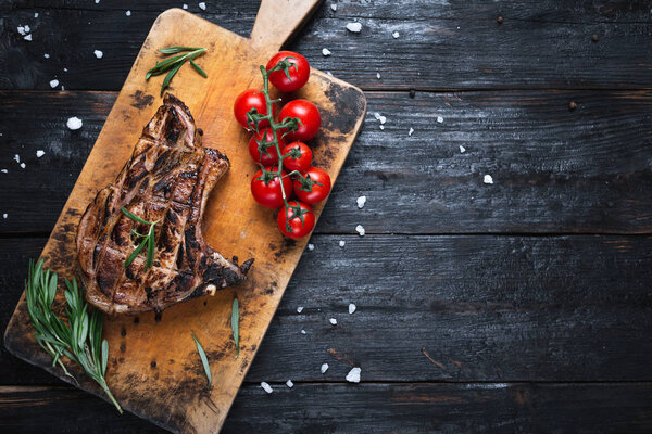 a piece of medium rare steak, fresh vegetables on the table, ripe tomatoes. Tasty dinner for the family