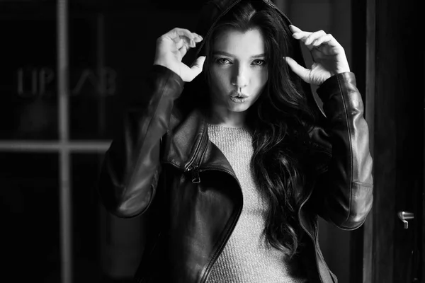 Gorgeous brunette girl with curly hair. Black and white photo. The lady is wearing a leather jacket. Her look is aggressive and seductive. — Stock Photo, Image