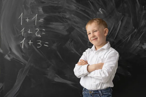 教室の黒板には頭のいい男子生徒が立って笑っている その少年の腕は胸に折られている 数学の例はボード上に書かれています 教室で正の学生 テキストの場所 — ストック写真