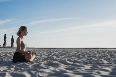 Doğayla birlik. Genç ve güzel bir kadın kumda oturur ve meditasyon yapar. Kamp temiz hava ve esinti. Uzayı kopyala Metin için yer