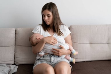 Mutlu aile kavramı. Genç ve güzel bir kadın kanepede oturuyor. Küçük bir çocuğu kollarına al. Mesaj için yer. Boşluğu kopyala