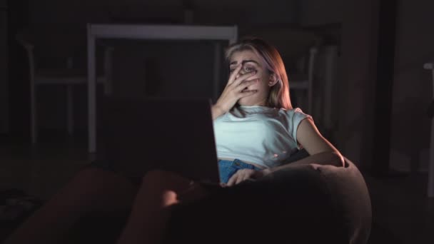 一个年轻的女人一个人坐在家里看恐怖片 电影在网上 最喜欢的电影总是有售的 晚上时间 — 图库视频影像