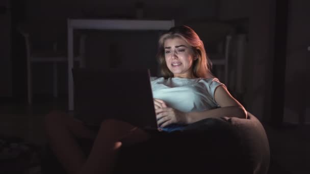 一个漂亮的女人坐在沙发上 晚上在家看恐怖电影电视 害怕的女孩在客厅看电视 电子游戏 休闲的概念 — 图库视频影像