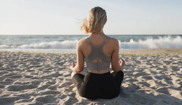 Young beautiful woman sits on the ocean. Early morning meditation. Calmness and unity with nature. — Stock Photo, Image
