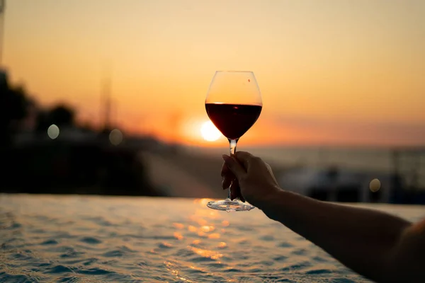 Female hand holds a side of wine against the background of the sun. Natural drink. — Stock Photo, Image