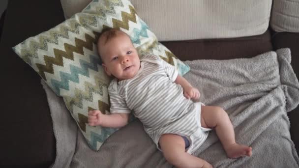 O bebé está deitado em casa numa almofada. Infância feliz. — Vídeo de Stock