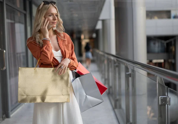 一个漂亮的女人带着购物袋在购物中心里的肖像在电话里交流 消费者概念 案文的位置 — 图库照片