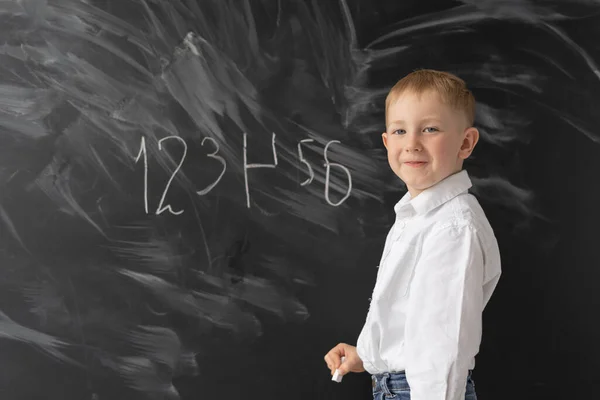 学校やオフライン教育で 6歳の少年が黒板の近くに立っている チョークで数字を書きなさい エラー完了タスク — ストック写真