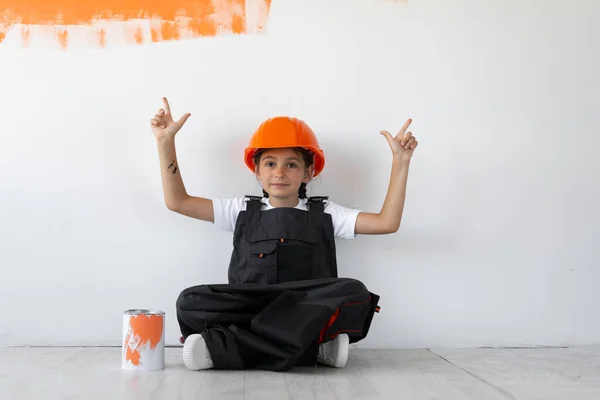 Девушка Одета Комбинезон Оранжевый Защитный Шлем Голове Сидя Полу Глядя — стоковое фото