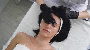 Güzellik uzmanının resepsiyonunda, güzellik uzmanının ellerini temizleyen genç bir kadın krem sürüyor..
