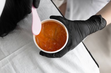 Ofisindeki profesyonel bir güzellik uzmanının yakın çekimi yanında yatan bir müşterisine uygulamak için portakal kremi maskesi alıyor. Gençleştirme ve yüz bakımı süreci