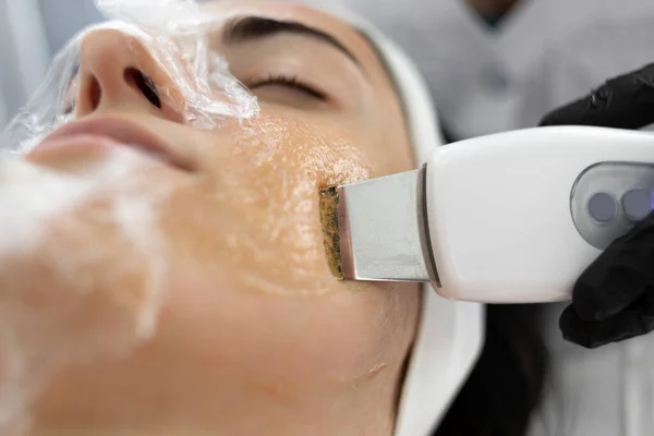 Beautiful young woman at the reception at the beautician, ultrasonic face cleaning close-up side view. Cosmetic procedure in a modern beauty salon. personal hygiene