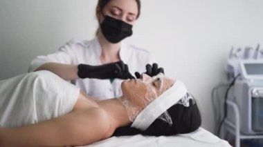 Güzellik uzmanının resepsiyonundaki genç ve güzel bir kadının yüzü kozmolojik bir filmle kaplıdır. Modern bir güzellik salonunda kozmetik prosedür.