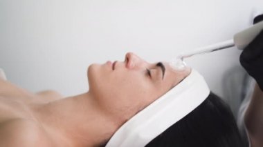 Güzellik salonundaki resepsiyonda genç ve güzel bir kadın. Nalbur temizliği ile yüz derisini dezenfekte ediyor. Yakın plan. Modern bir güzellik salonunda kozmetik prosedür.