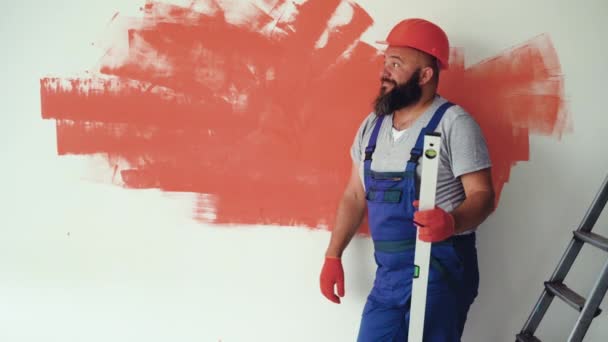 Ein Bärtiger Mann Trägt Anzuguniform Und Schutzhelm Die Wand Gelehnt — Stockvideo