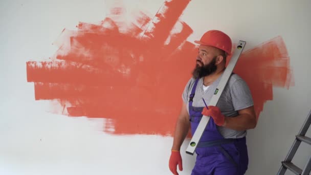 Ein Bärtiger Mann Trägt Anzuguniform Und Schutzhelm Die Wand Gelehnt — Stockvideo