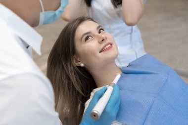 Kadın hasta dişçide sandalyeye oturur ve dikkatle doktoru dinler. Diş hastalıklarının önlenmesi