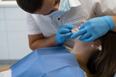 Erkek dişçi kadının üzerine eğildi ve çenesine baktı. Diş hastalıklarını önleme kavramı