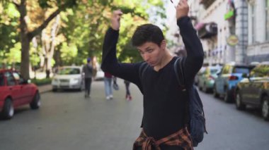 Genç beyaz erkek turist sokakta durup kulaklık takıyor ve müzik dinliyor. Yüksek kalite 4k görüntü