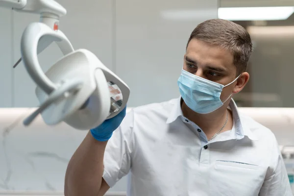 Close-up of the doctor\'s face, he shines a lamp at the patient.