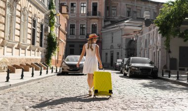 Sarı bavullu bir kız eski şehrin sokaklarında dolaşıyor..