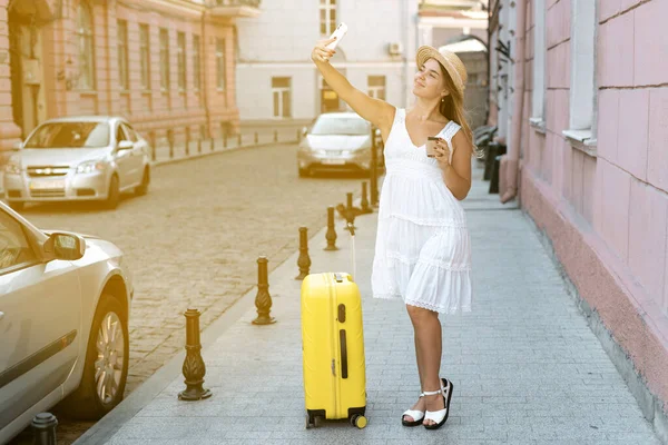 Ευτυχισμένο χαμογελαστό κορίτσι πηγαίνει διακοπές με μια μεγάλη κίτρινη βαλίτσα. — Φωτογραφία Αρχείου