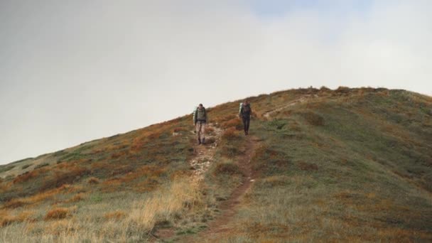 Hombre y mujer descienden de la cima de la montaña. La chica corre y se regocija. — Vídeos de Stock