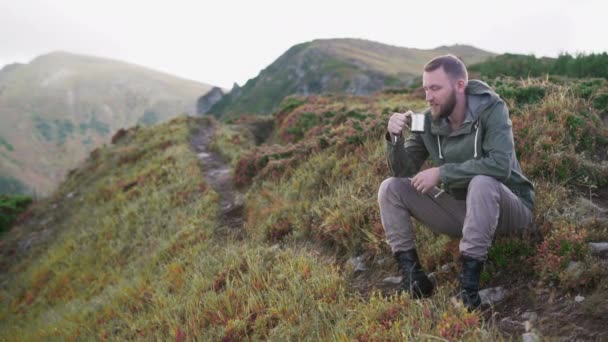 Turista maschio si siede sulla cima del pendio bere delizioso caffè — Video Stock