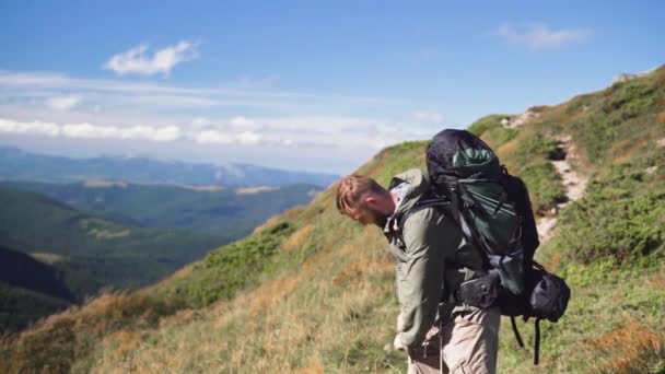 男の観光客は山の上に立って紙の地図を取り出し — ストック動画
