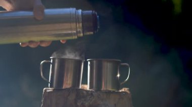 Buhar bir bardağın üzerinde yükselir, sıcak bir içecek termostan diğerine dökülür.