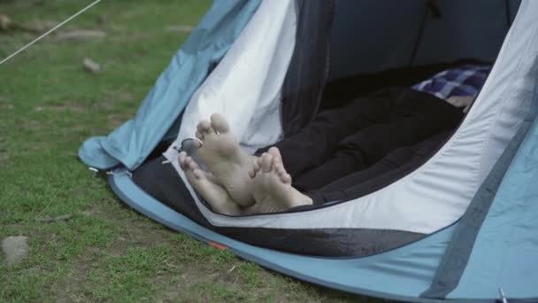 Dos pares de patas asoman desde la tienda, concepto de recreación al aire libre — Vídeo de stock