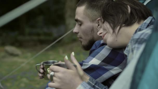 Jovem lindo casal europeu está sentado em uma tenda. Beber chá ao ar livre — Vídeo de Stock