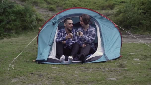 Birbirine aşık çiftler çadırda oturur sıcak bir şeyler içer ve sohbet ederler. — Stok video